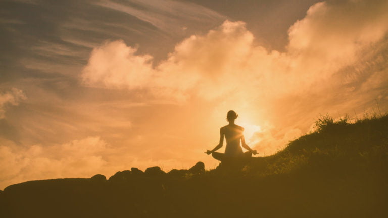 Person Meditating on a Mountain Cliff with Sunset - Letting Go of the Past through Meditation and Mindfulness